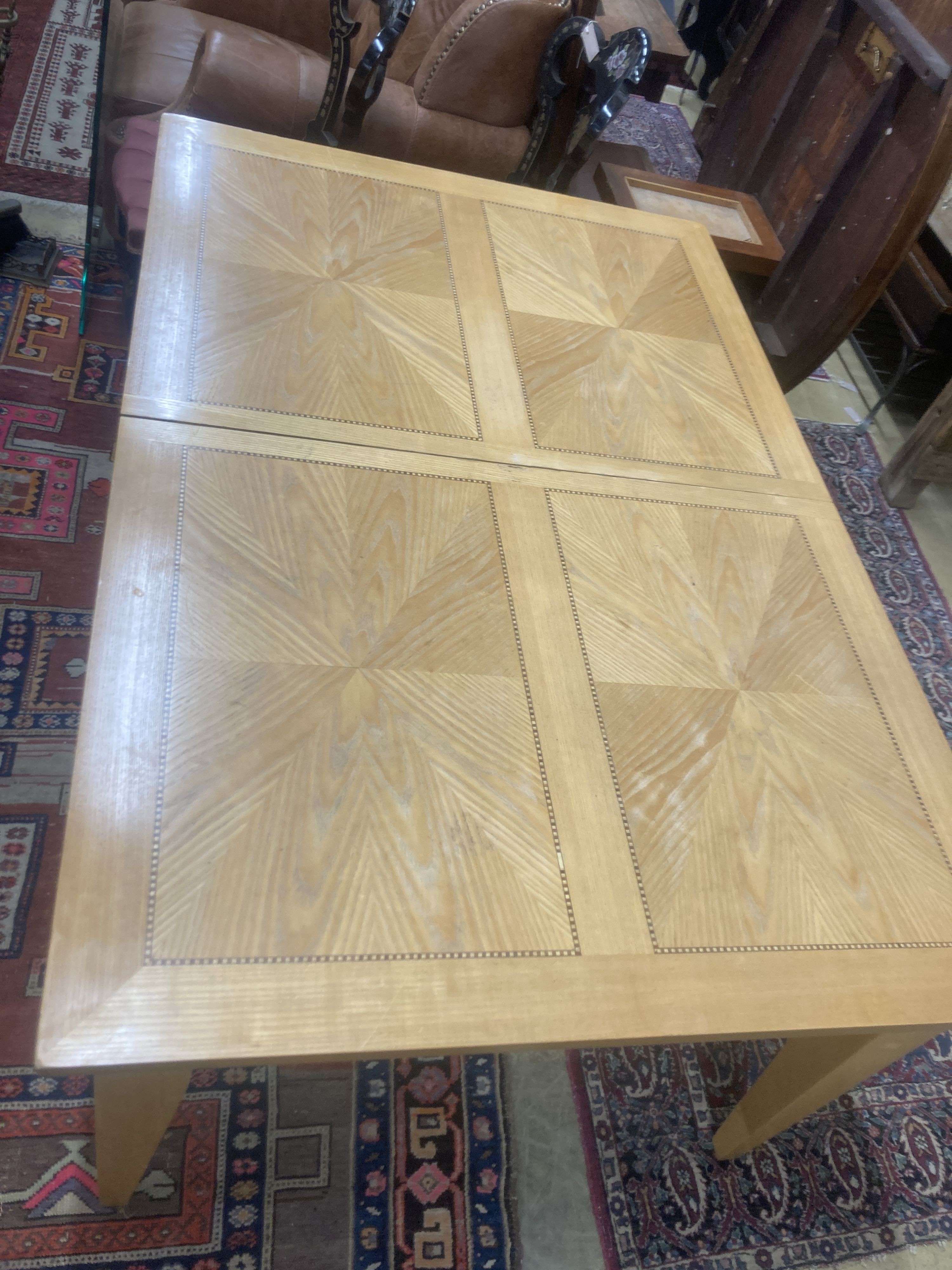A contemporary inlaid oak extending dining table, 236cm extended, two spare leaves, W.106cm H.75cm